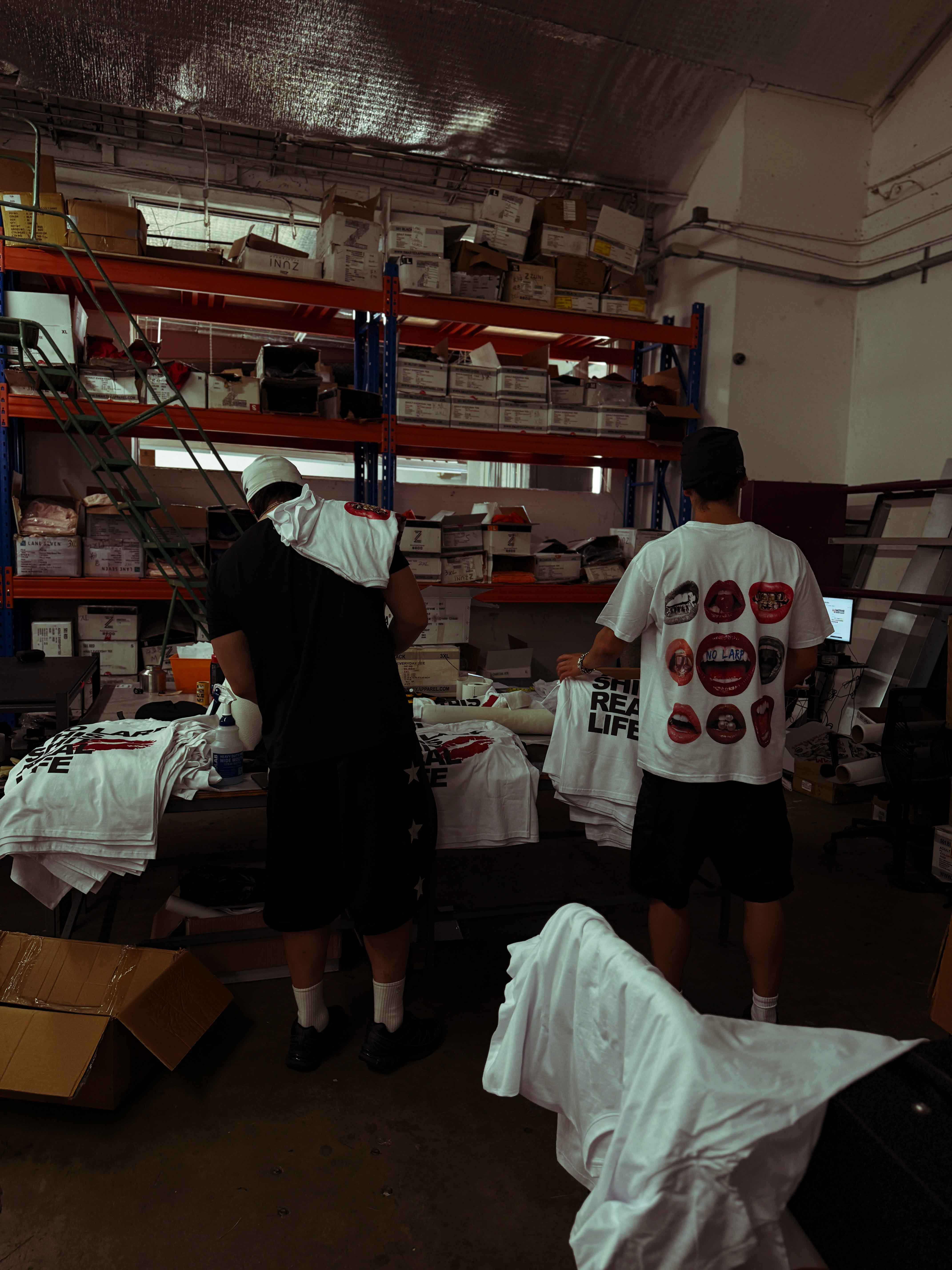 Back of a white No LARP T-shirt in a working warehouse